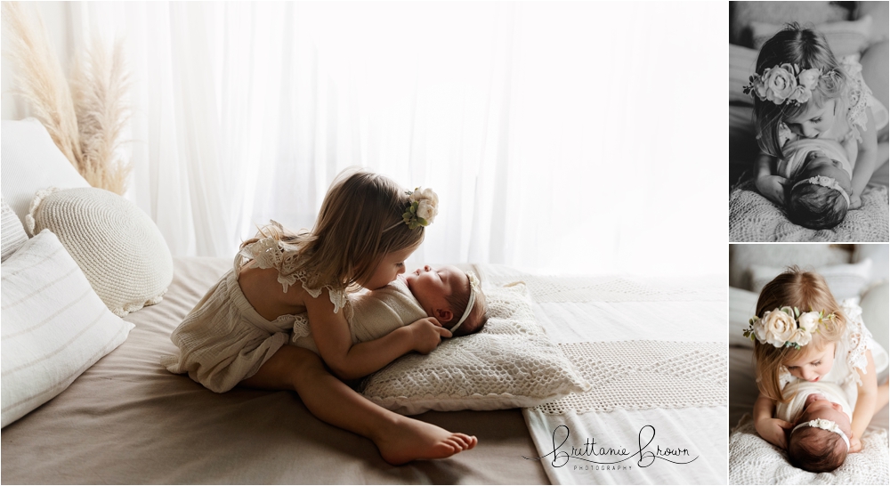 Newborn Sibling Session in Georgetown KY with Big sister holding her newborn baby sister on a cozy white bed.