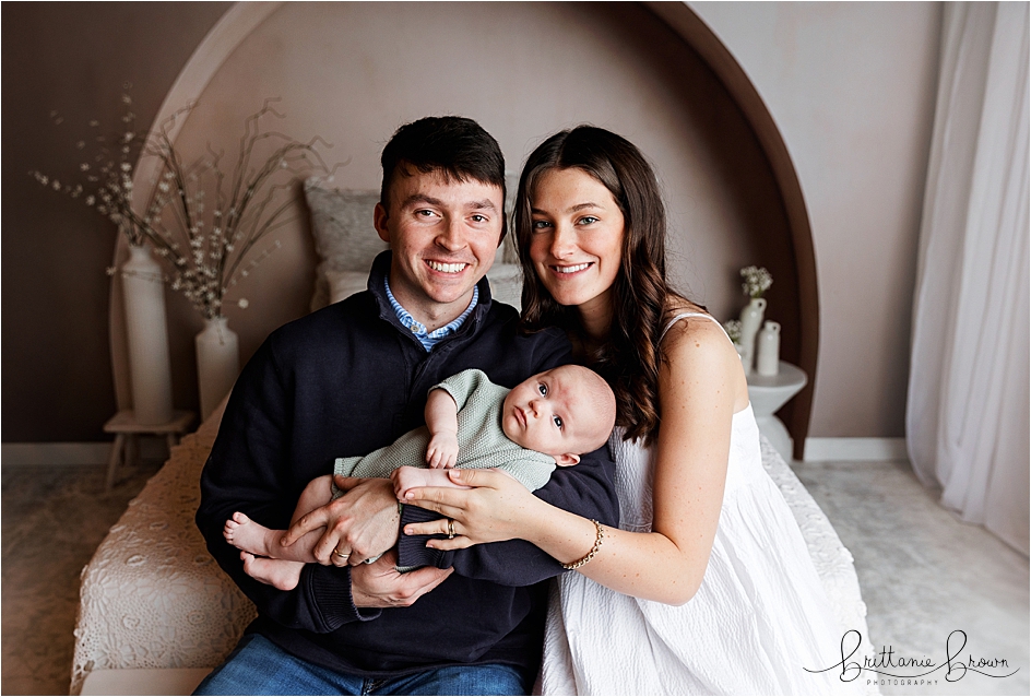 Mom and dad holding one month old baby for pictures.