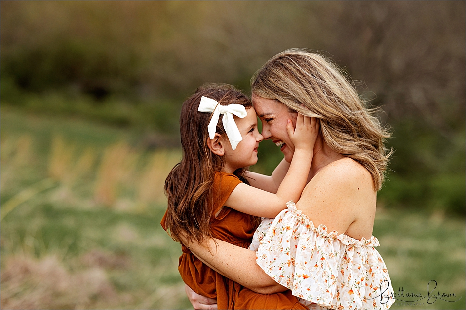 Mom and daughter nose to nose in a close up outdoor family image.